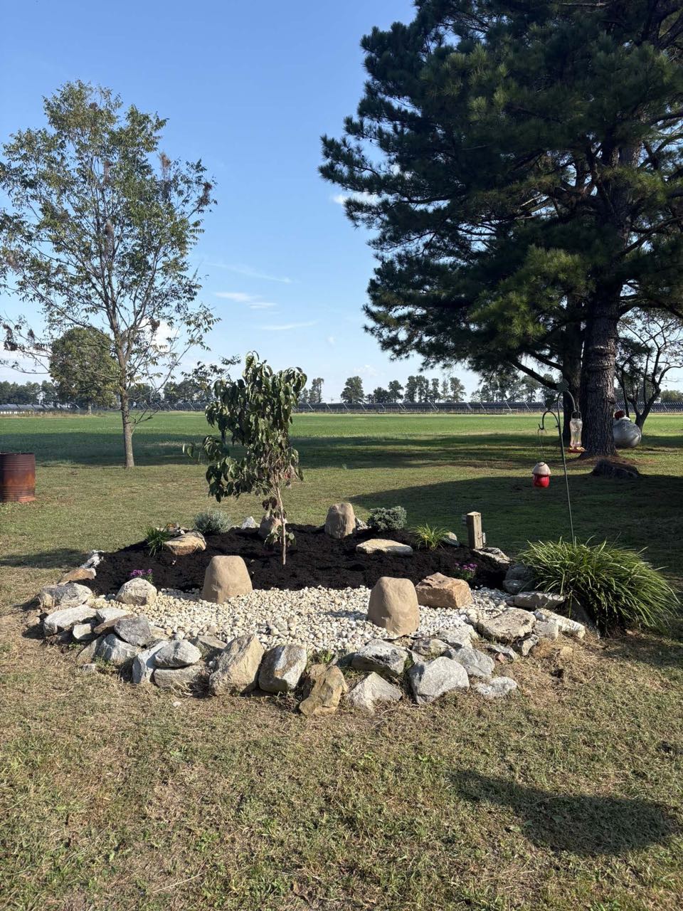 A stone rock-garden island bed with new plantings built by SEMO LawnCare & Landscaping near Sikeston, MO